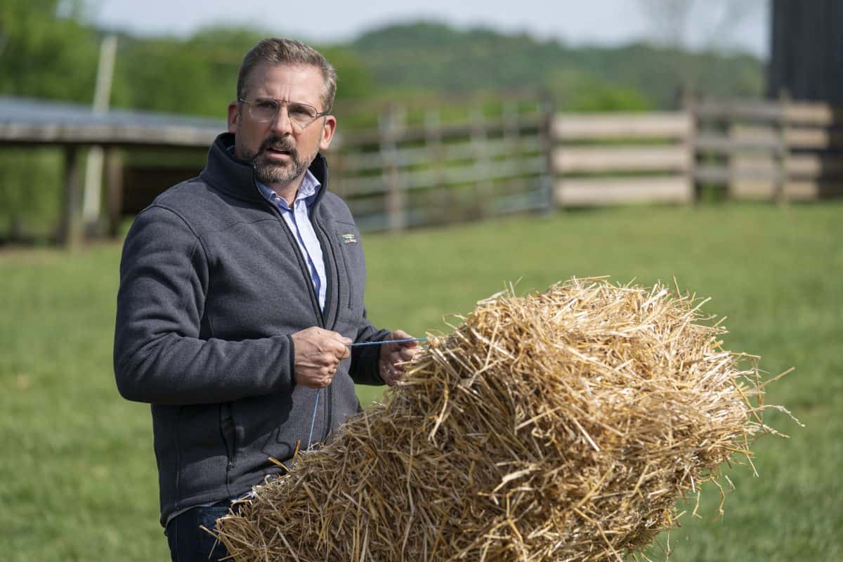 Steve Carell auf dem Land mit einem Heuballen in den Händen, schaut etwas verwirrt.