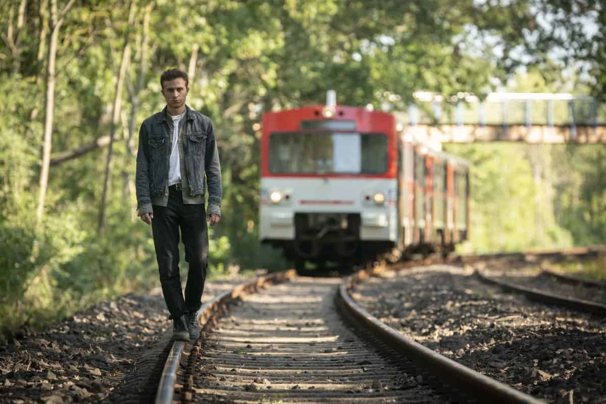 Max Hubacher balanciert auf einem Gleis. Ein Zug kommt hinter ihm angefahren