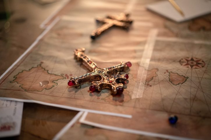 Ein Kreuz liegt auf einer Landkarte im Film Uncharted