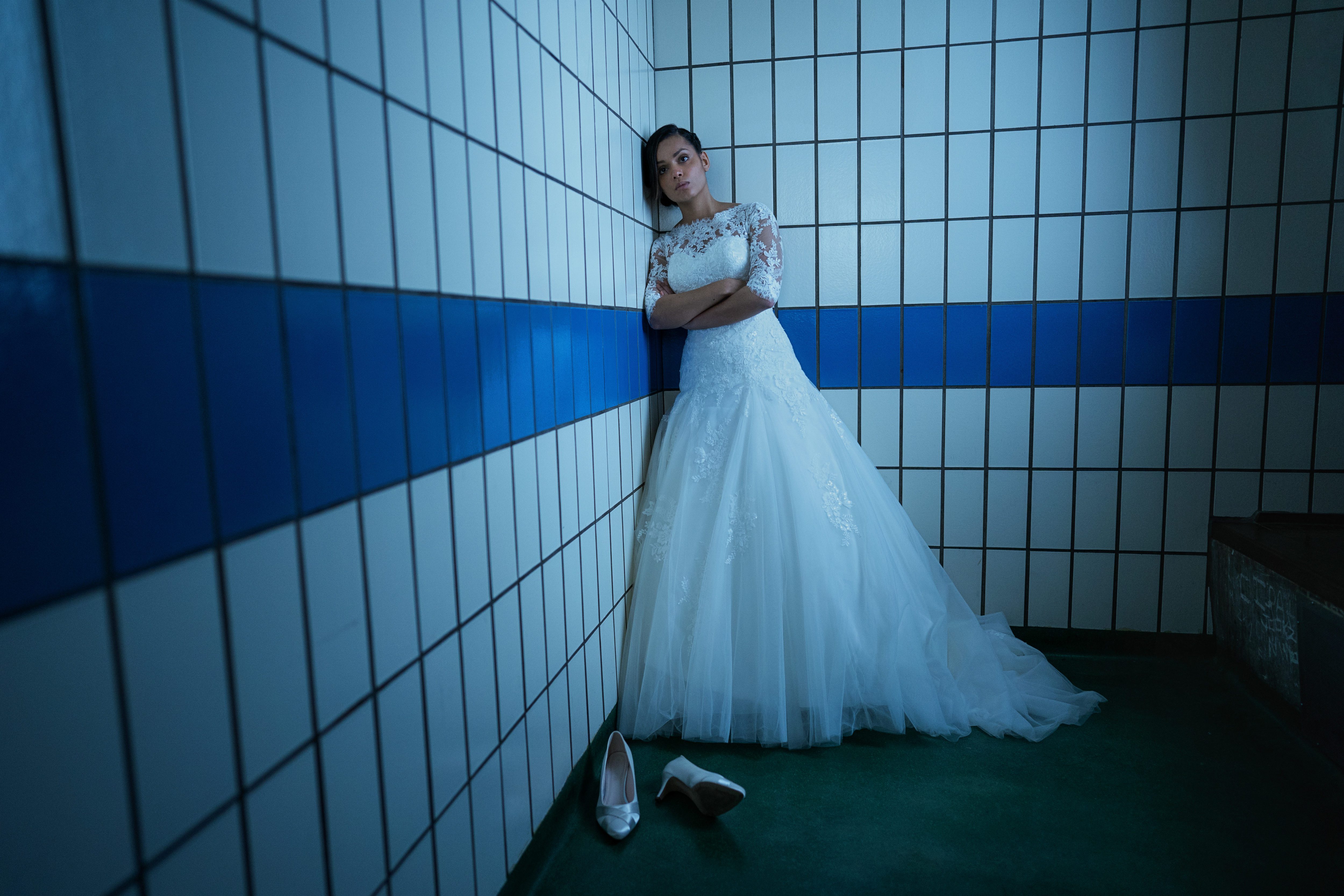 Eine Frau im Hochzeitskleid in einen kahlen raum mit Fließen 