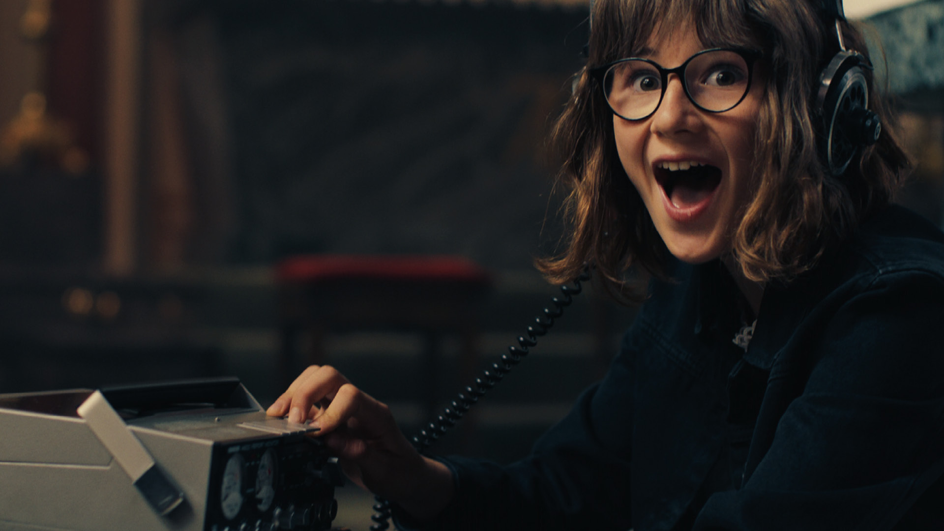 Ein Mädchen mit Brille und Kopfhörern, freut sich über Radio Empfang