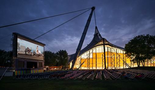 Kino Am Olympiasee München, mit der beleuchteten Olympia-Schwimmhalle im Hintergrund